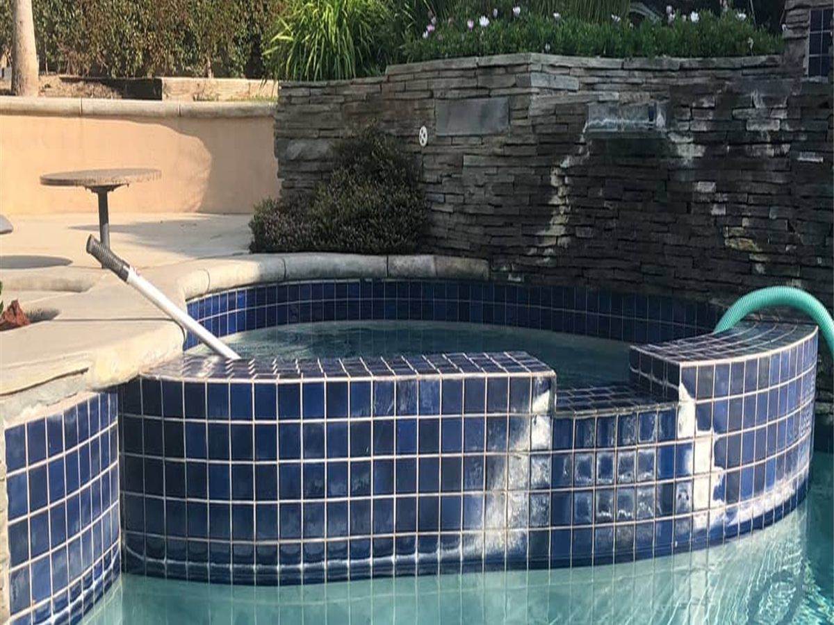Navy spa tile with white calcium crust along the top rows before bead blasting
