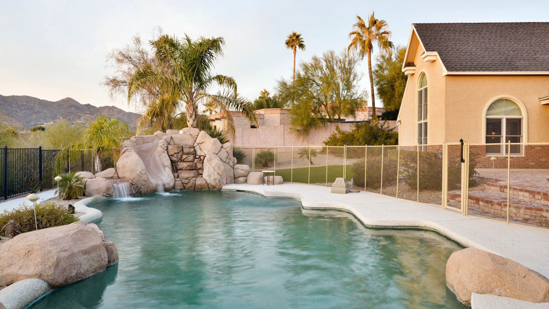Cloudy green backyard pool with a rock waterfall before cleanup