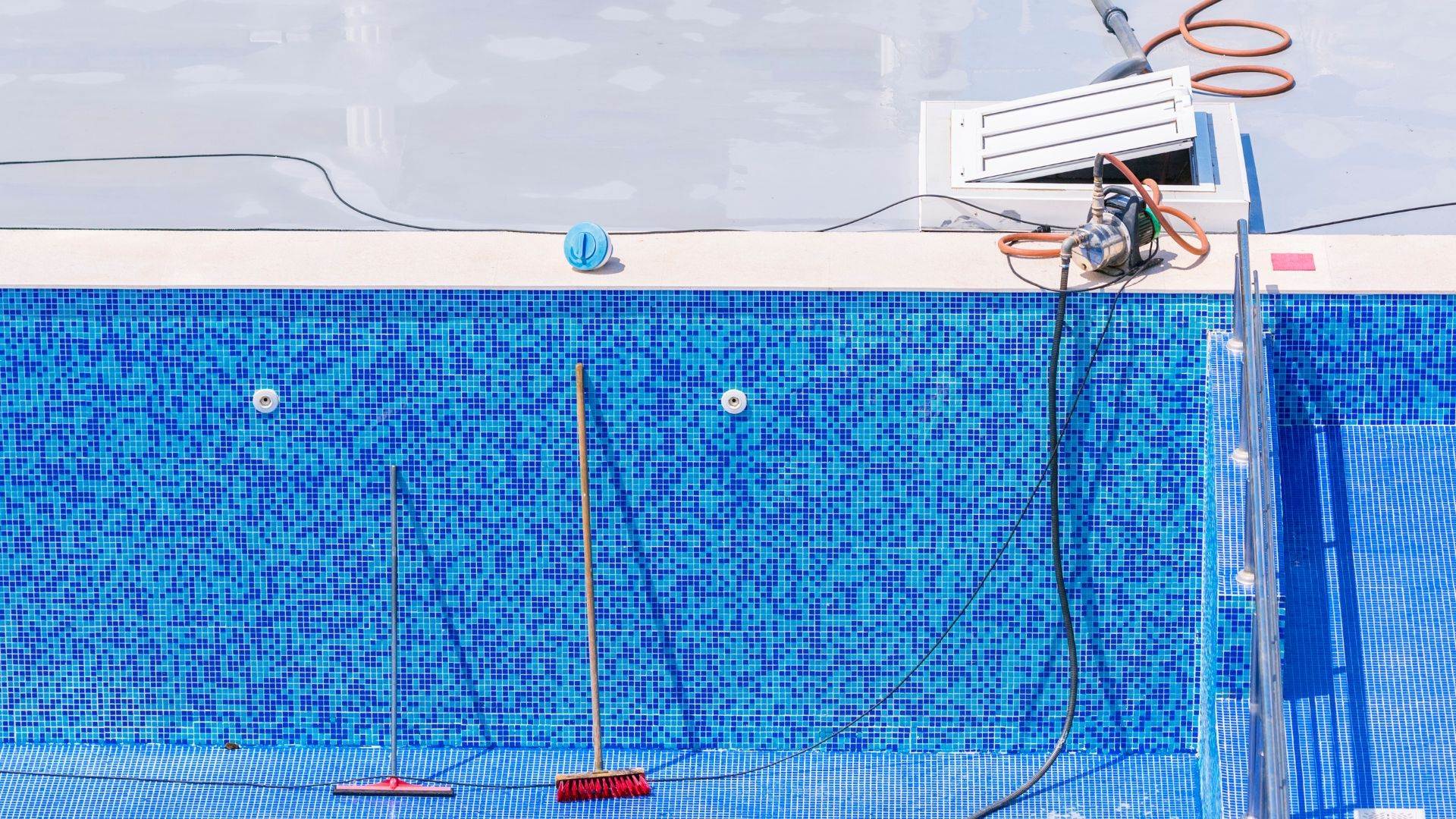 Drained pool with brushes and a pressure unit set up for an acid wash