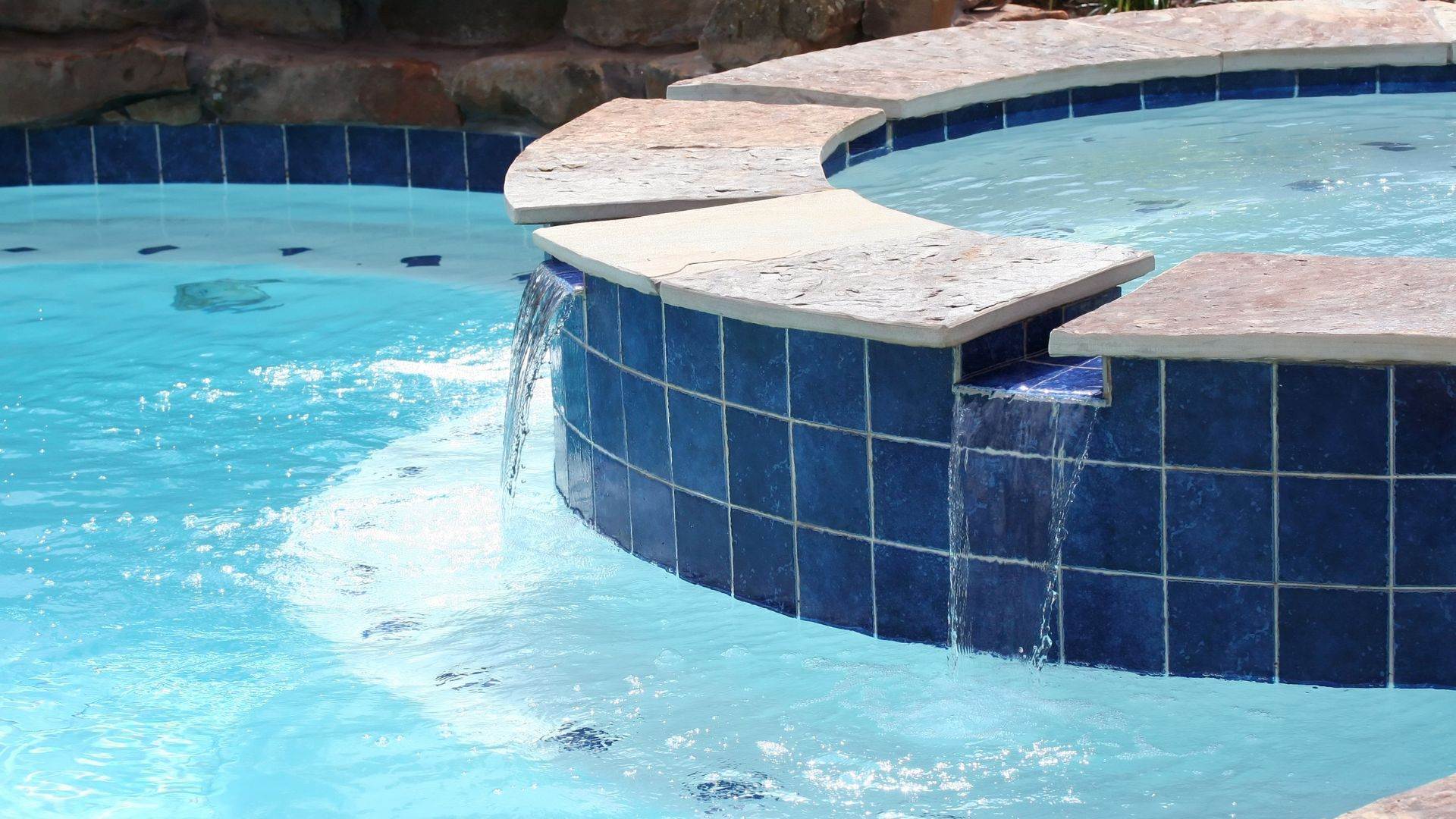 Navy waterline tile on a raised spa wall after pool tile cleaning