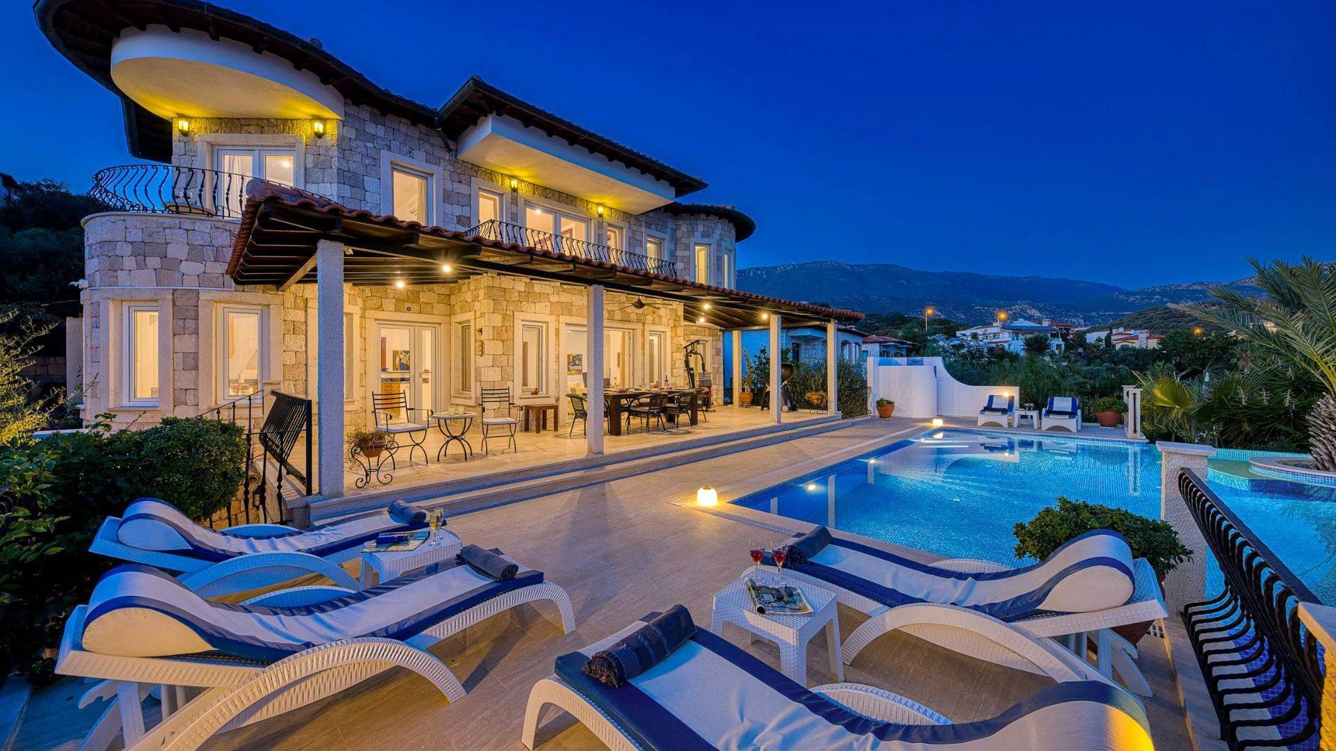 Salt water pool lit at dusk beside a stone patio