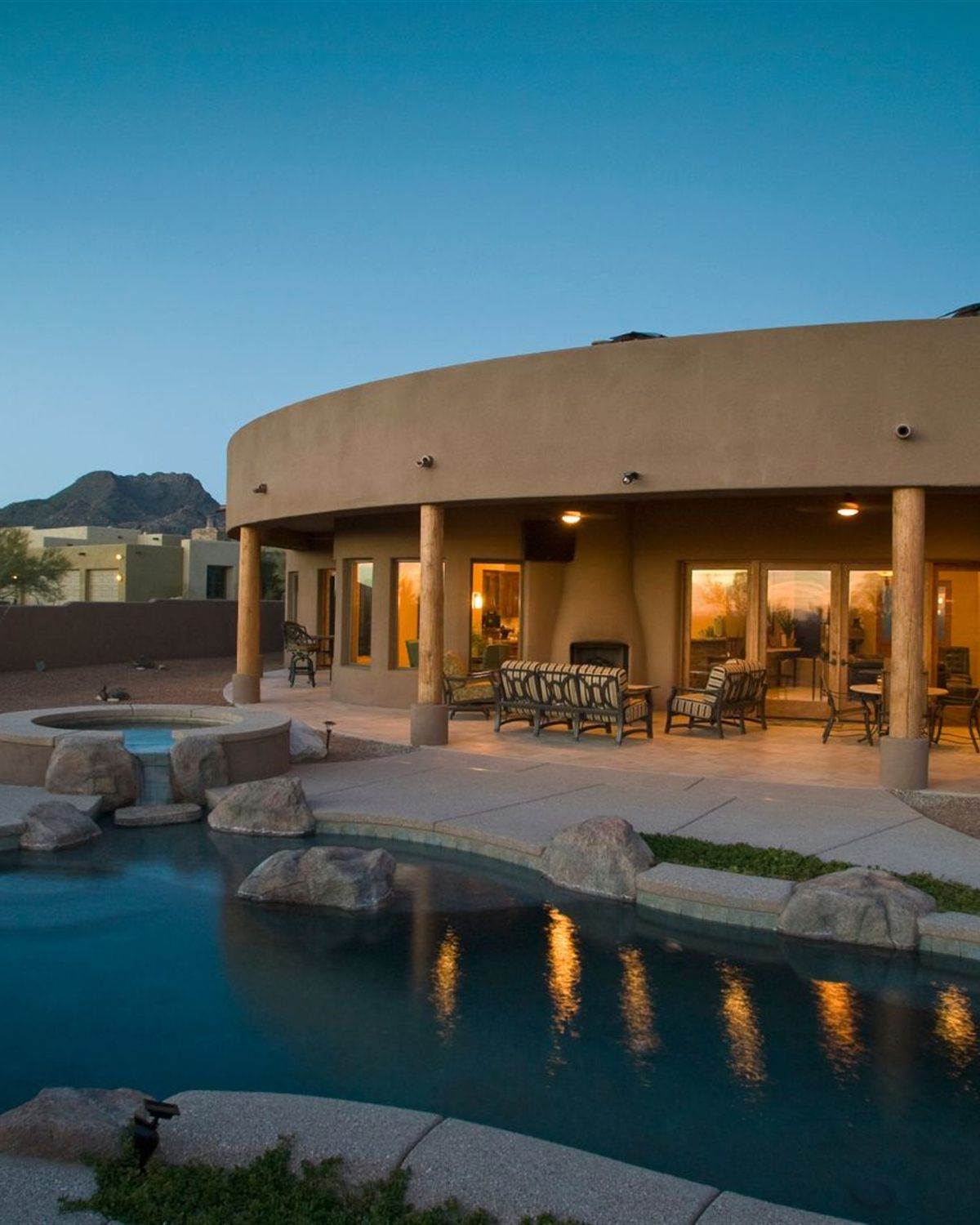 Desert backyard pool at dusk with boulders and planting