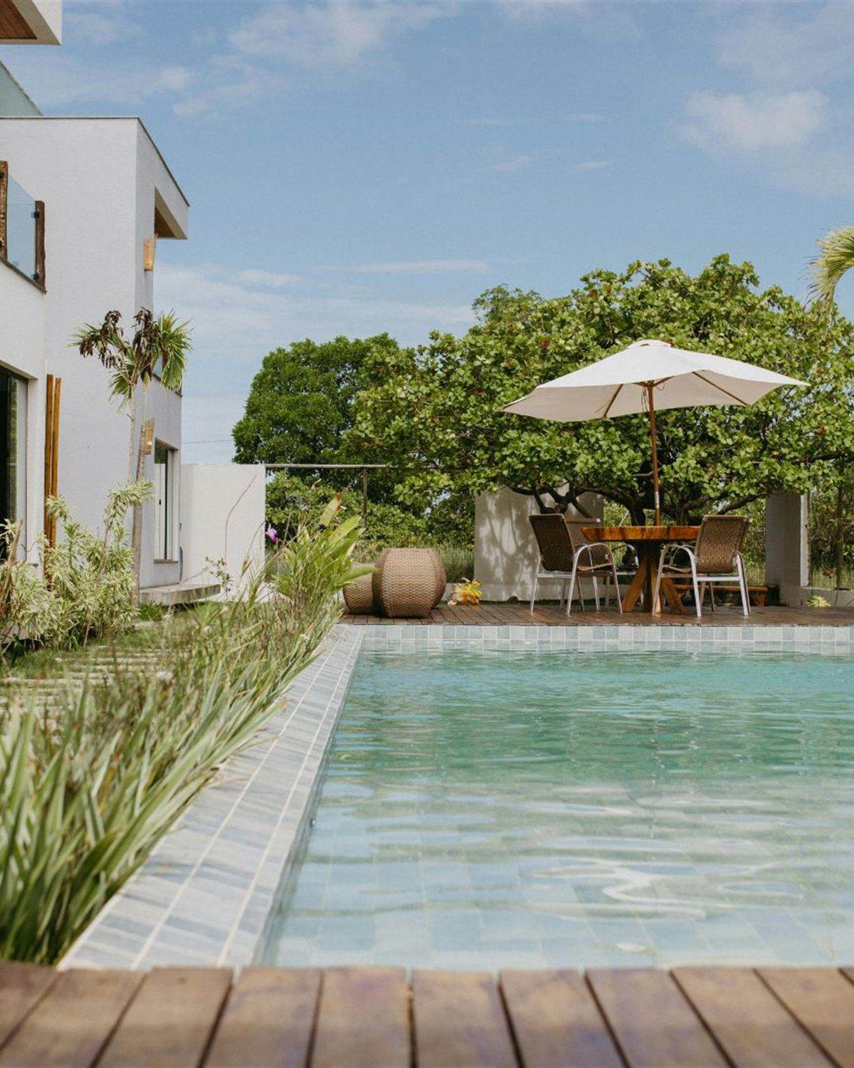 Rectangular pool with a wood deck and dining furniture