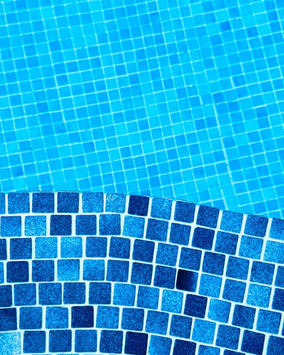 Waterline tile band running along the edge of a bright blue swimming pool