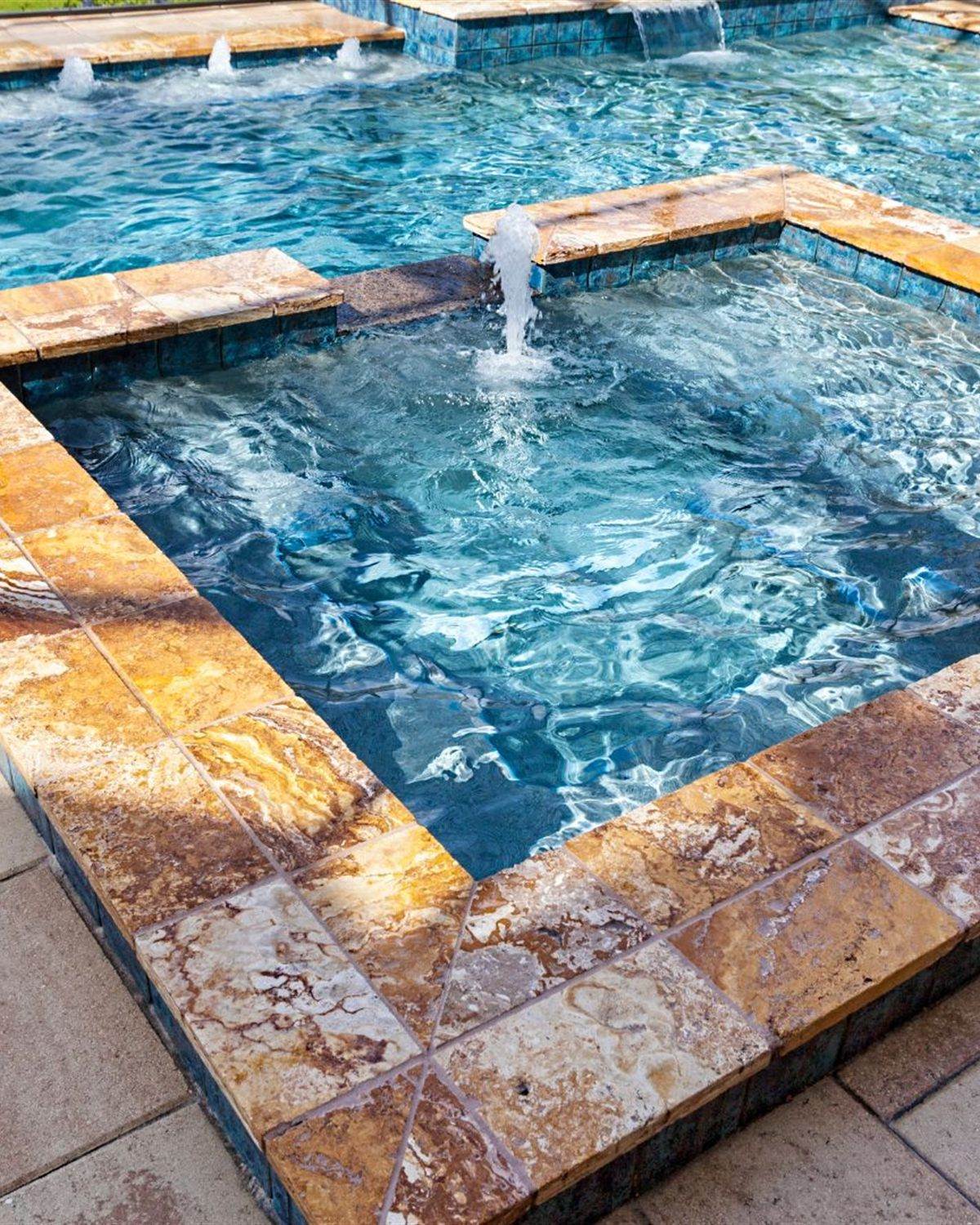 Raised spa and pool with stone coping and blue waterline tile in an Arizona backyard