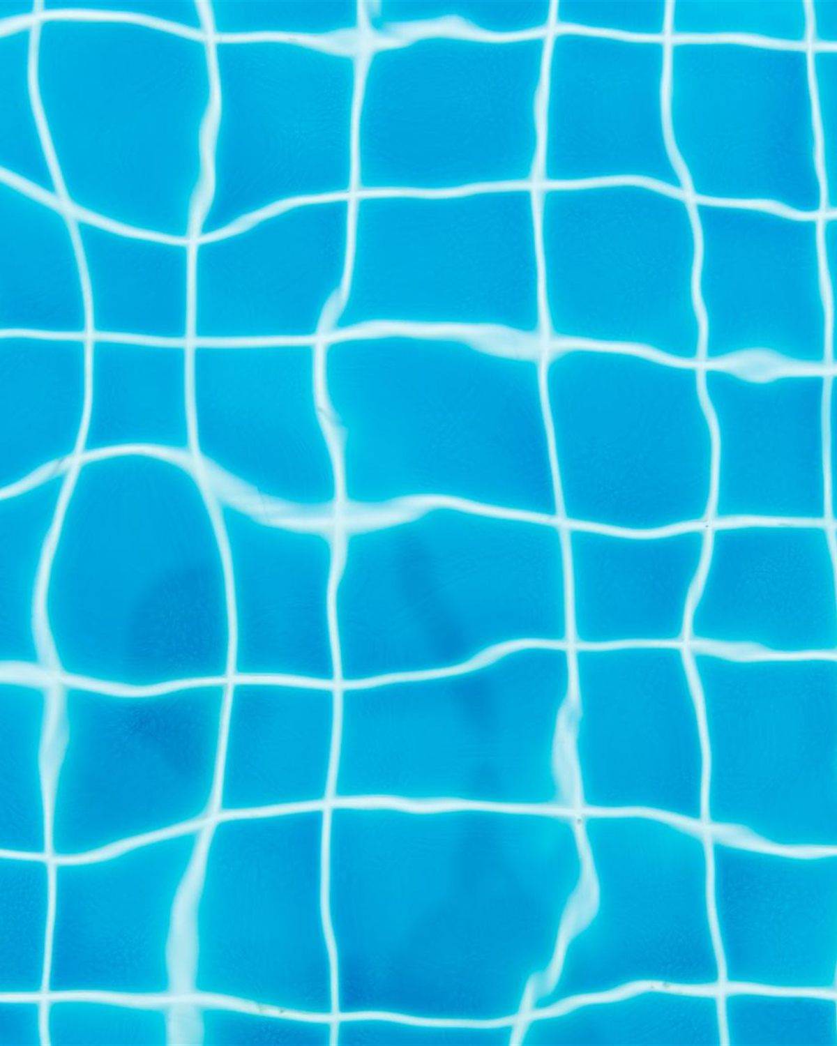 Bright cyan pool floor tile seen through rippling water