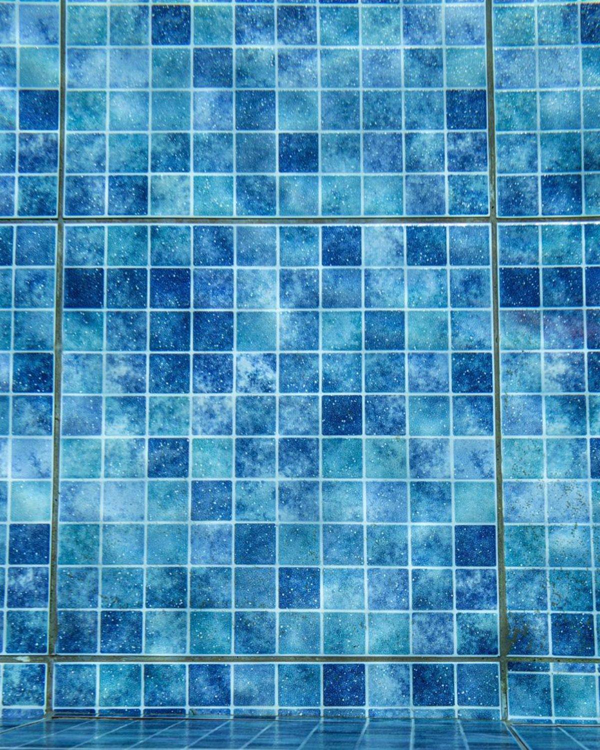 Deep blue glass mosaic tile on a pool wall seen underwater